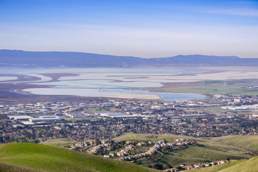 A scenic hilltop view of Milpitas, California, showcasing the cityscape, residential neighborhoods, and surrounding hills.