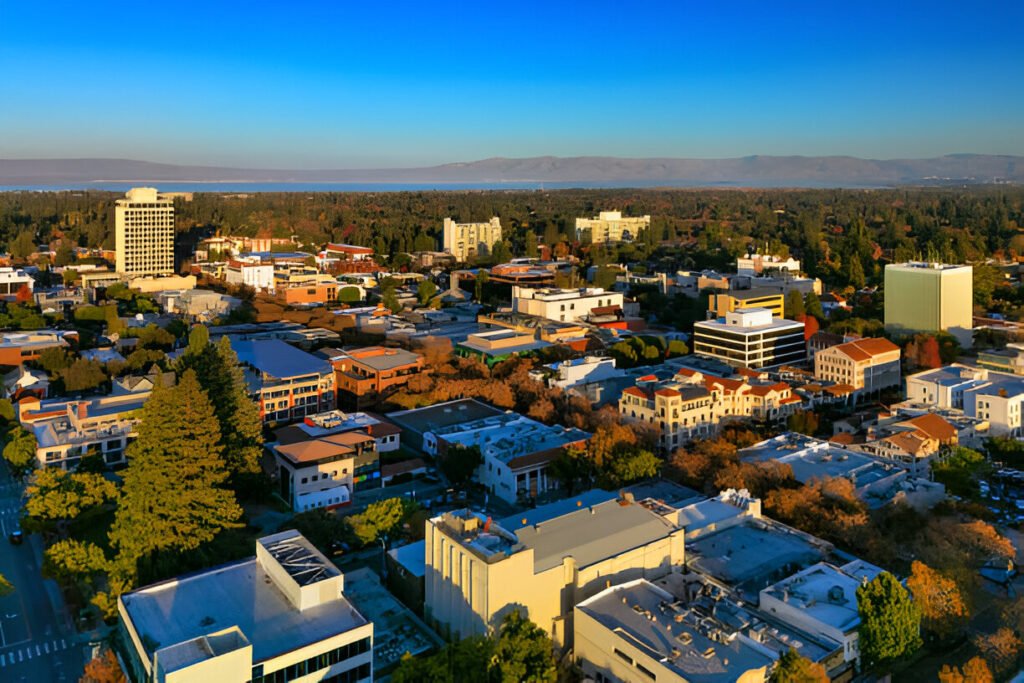 Aerial view of Palo Alto downtown with the San Francisco Bay and mountain range in the background.