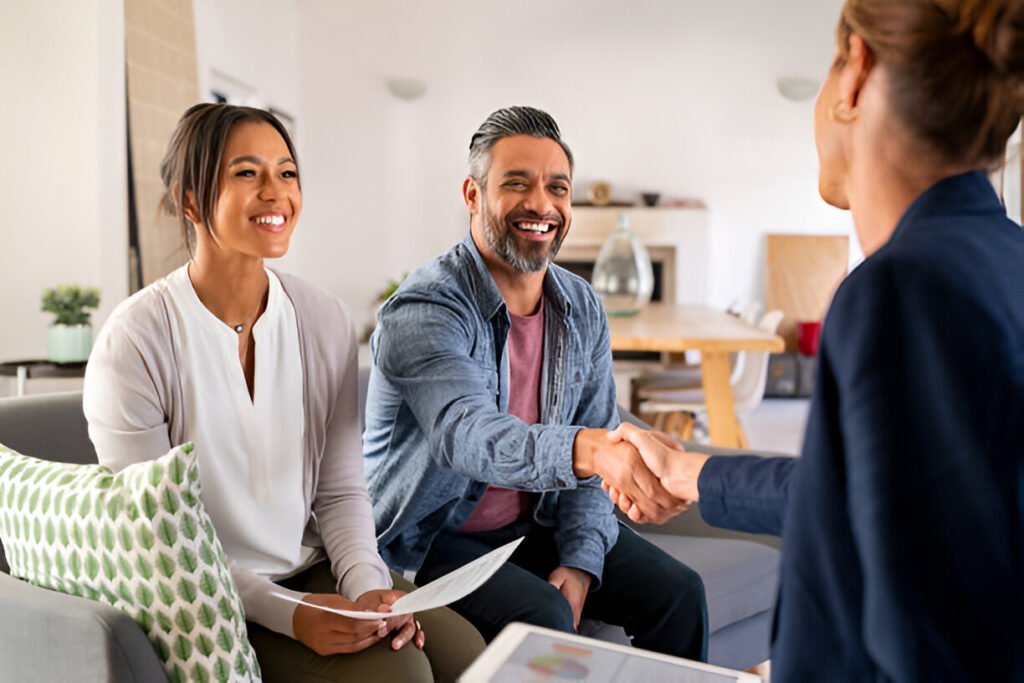 A multiethnic couple shaking hands with a real estate consultant at home, finalizing a property deal in the San Francisco Bay Area.